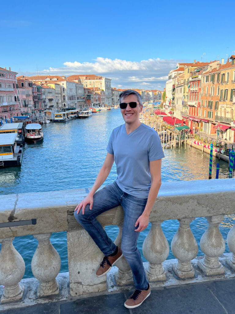 Nate Hake smiling for a photo with the canal in Venice on his background